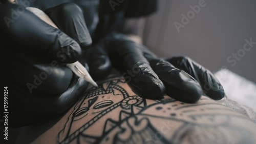 Wallpaper Mural Macro view on professional tattoo master is painting tattoo with black ink, making cover. Works in black latex gloves with handmade rotor gun machine in his studio Torontodigital.ca