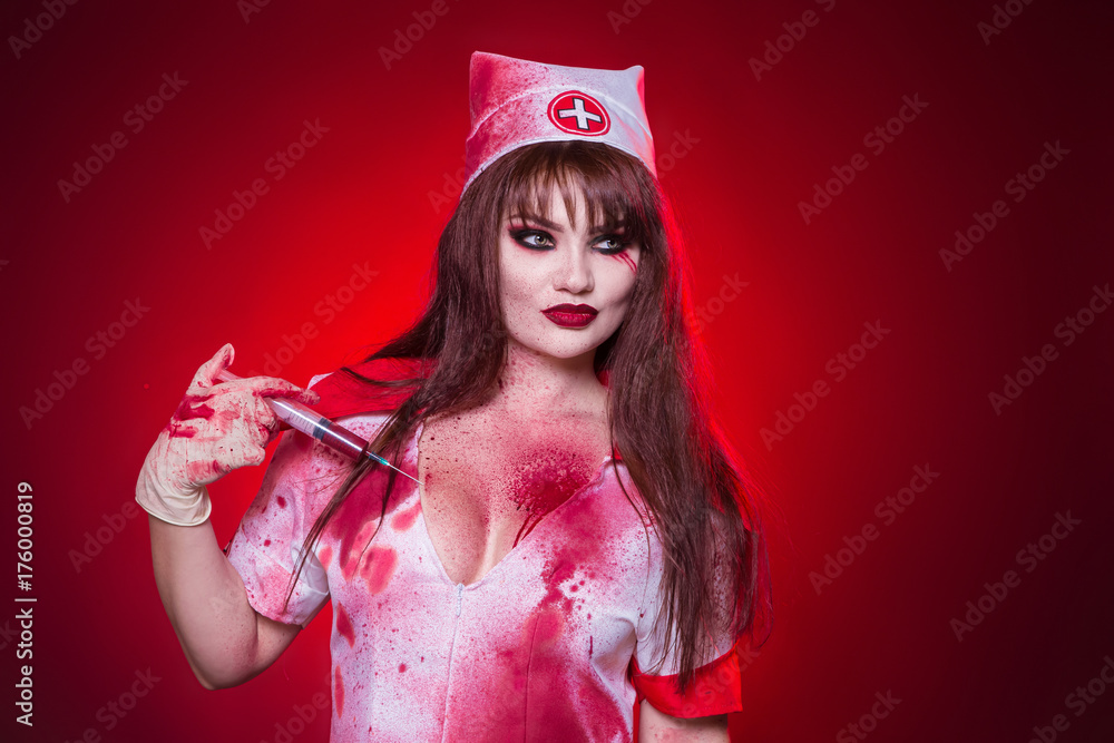 Beautiful, sexy, a woman in a nurse's suit, with a large notch on the chest holding a syringe with blood. Injections into the chest. The girl in the medical gown is covered in blood.  party Halloween