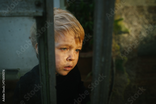 Little girl looking with interest and bewilderment at a bug (unseen) on a glasshouse wall.