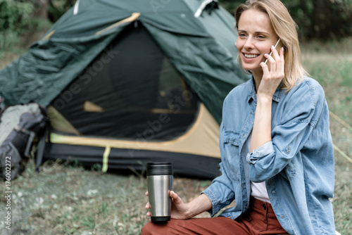 Happy young woman speaking by cellphone in the nature