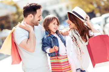 Happy family with little child and shopping bags in city.