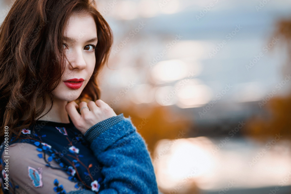 Obraz premium Closeup portrait beautiful curly young girl looking to camera wearing blue coat and dress in autumn park