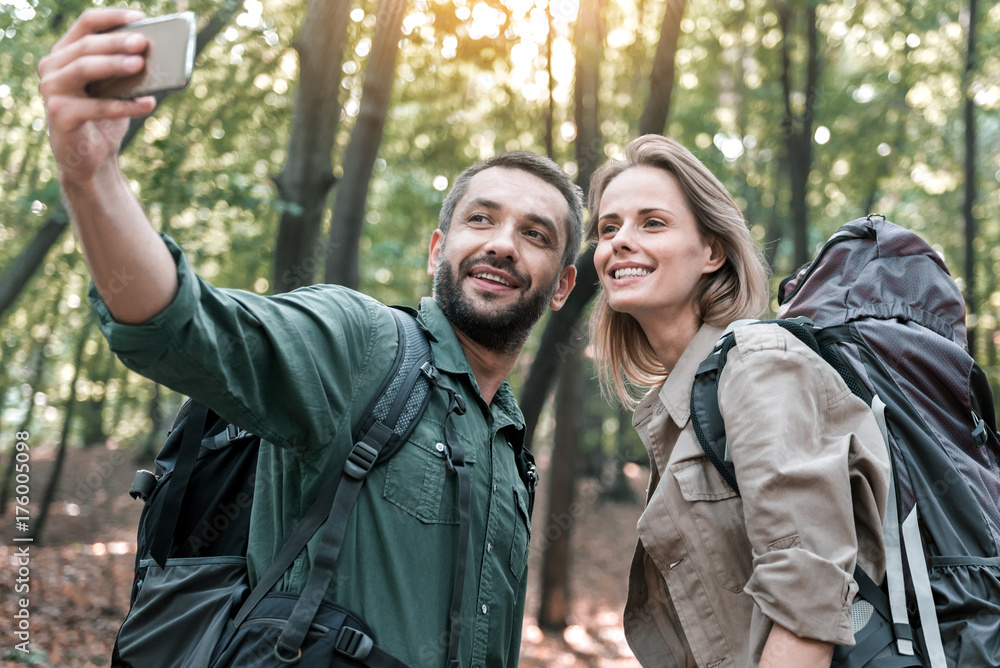 Happy man and woman photographing themselves on smartphone in nature