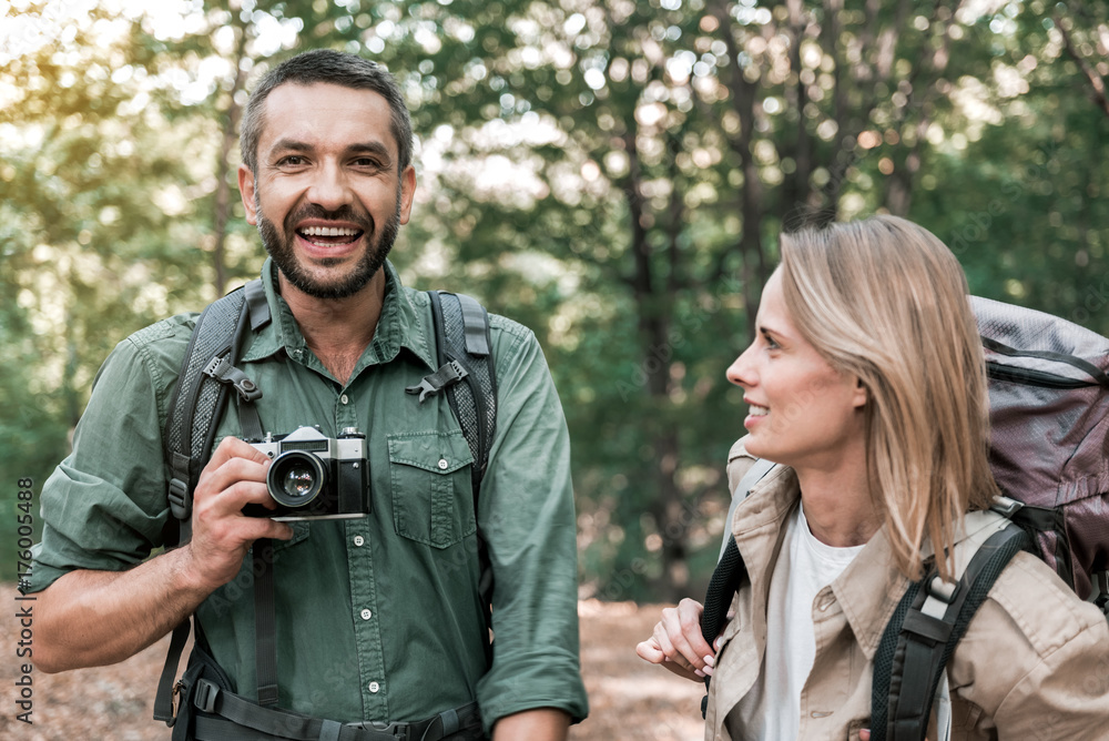 Cheerful married couple photographing forest during journey