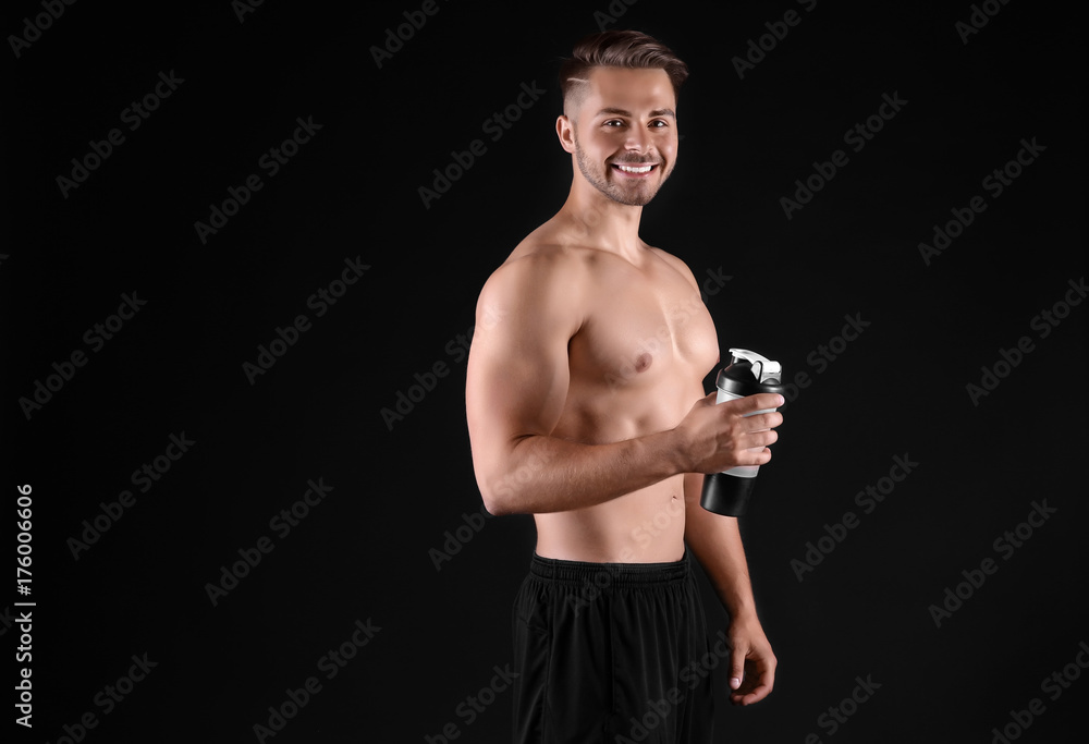 Sporty young man with bottle of water on black background