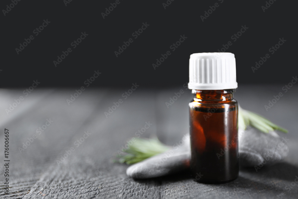 Bottle with rosemary oil and herb on wooden table