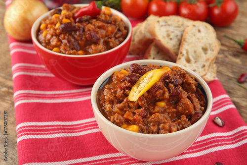 Chili con carne with fresh pepper in bowls on cloth