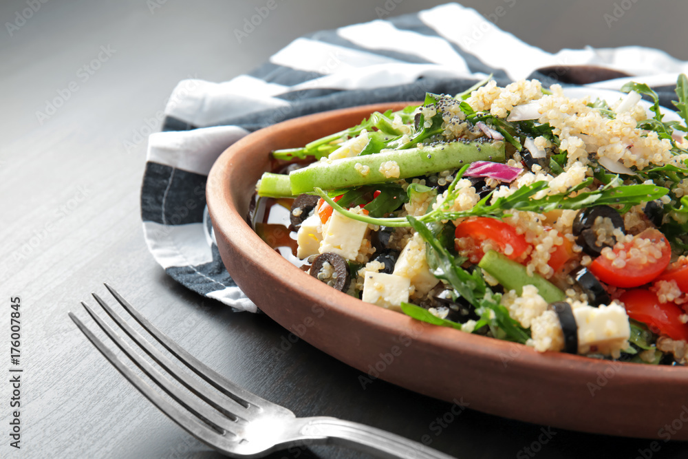 Wooden plate with quinoa salad on table, closeup Wooden plate with quinoa salad on table, closeup