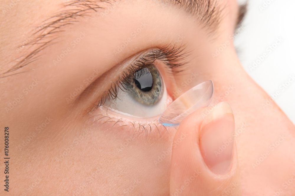 Obraz premium Young woman putting contact lens, closeup