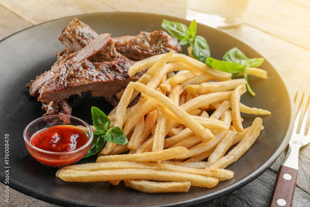Plate with delicious grilled steak frites on kitchen table Plate with delicious grilled steak frites on kitchen table