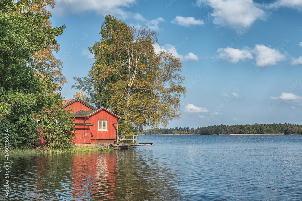 Obraz premium Picture of red wooden scandinavian style house at the lake during autumn