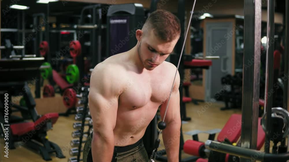 Shirtless attractive man training triceps using crossover in the gym. Muscular body, closeup view. Shot in 4k Shirtless attractive man training triceps using crossover in the gym. Muscular body, closeup view. Shot in 4k