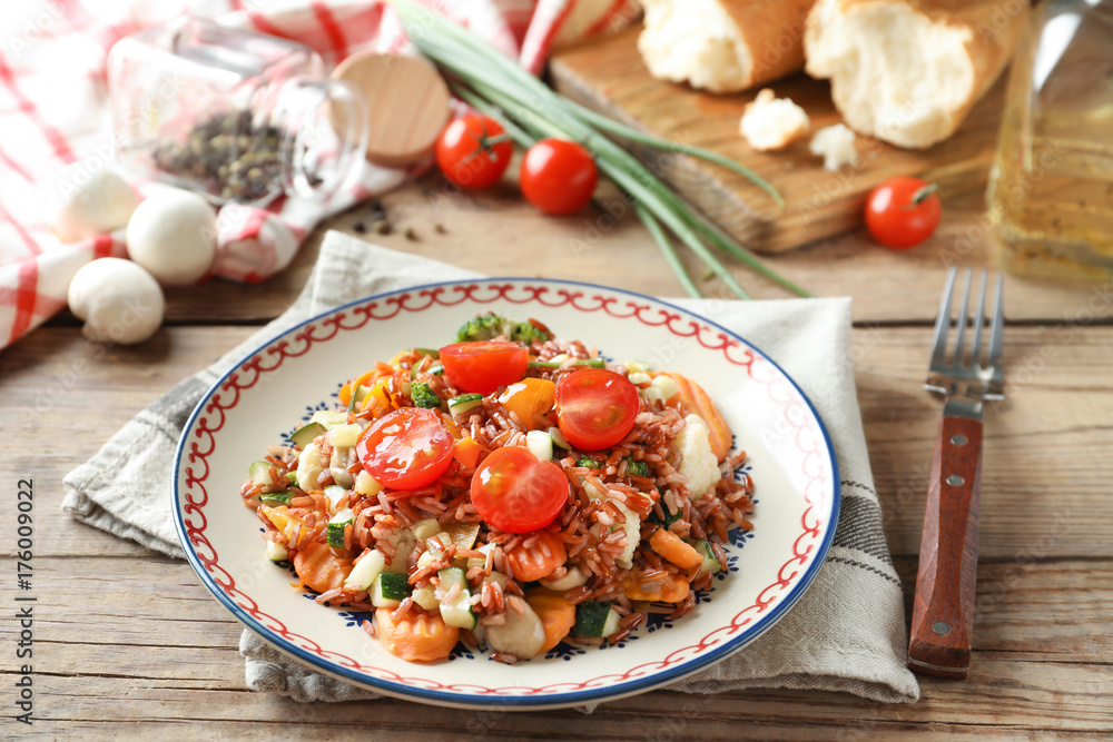 Plate with tasty brown rice and vegetables on wooden table Plate with tasty brown rice and vegetables on wooden table