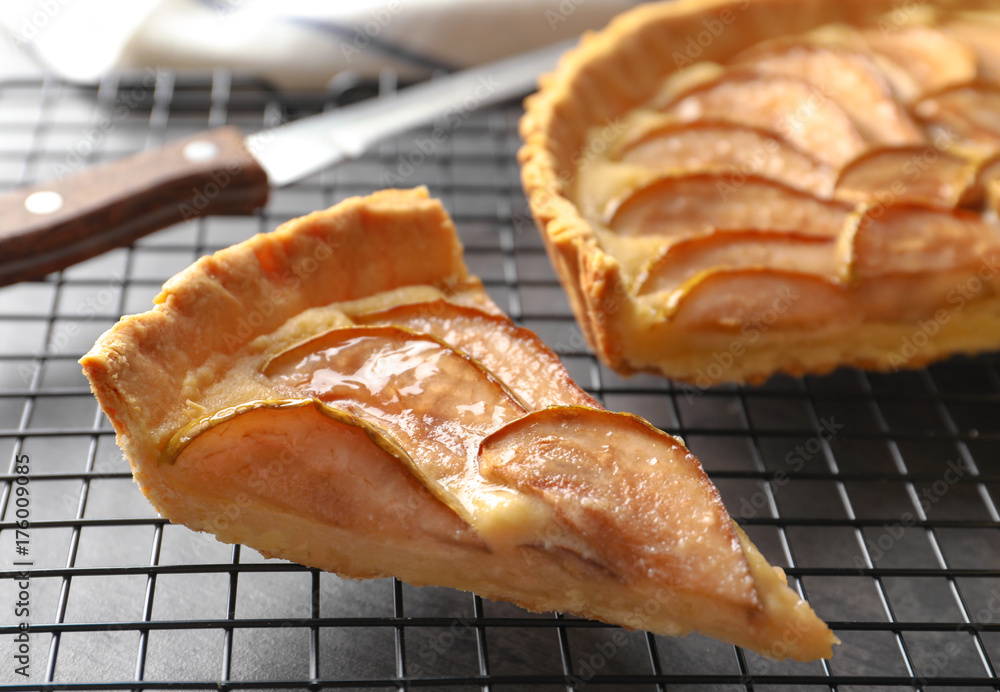 Cooling rack with piece of tasty pear tart on table Cooling rack with piece of tasty pear tart on table