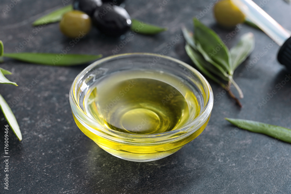 Glass bowl with olive oil on dark background Glass bowl with olive oil on dark background