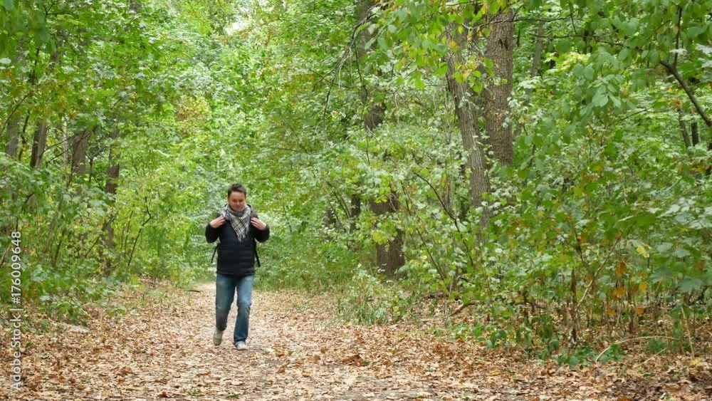 Cute Man Walking in Forest Between the Trees in Forest or City Park in Autumn. Smiles and Legs Kicks Yellow Fallen Leaves Cute Man Walking in Forest Between the Trees in Forest or City Park in Autumn. Smiles and Legs Kicks Yellow Fallen Leaves
