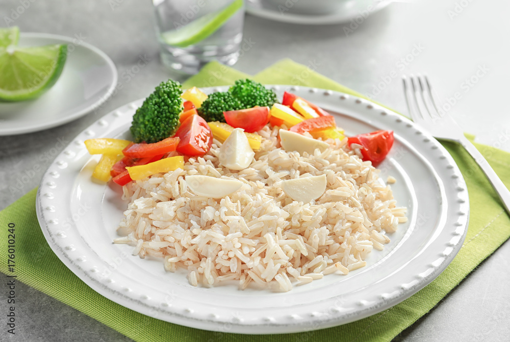 Plate with delicious brown rice and vegetables on table Plate with delicious brown rice and vegetables on table