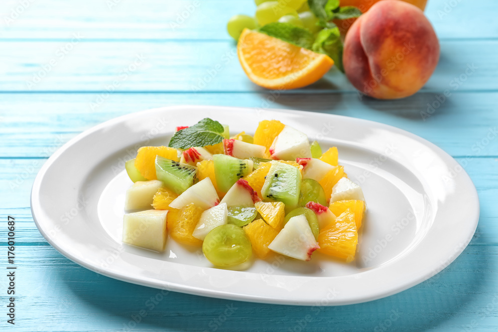 Plate with delicious fruit salad on wooden background Plate with delicious fruit salad on wooden background