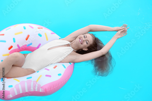 Beautiful young woman relaxing on inflatable donut in swimming pool © Africa Studio