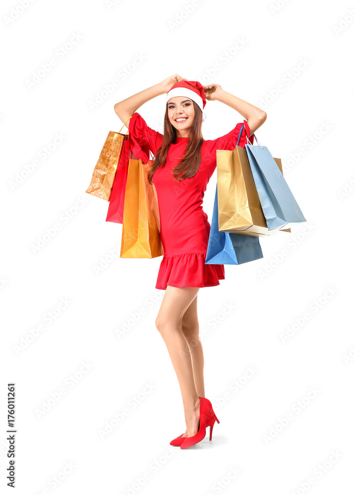 Beautiful young woman in Santa Claus hat and with bags on white background. Christmas shopping concept