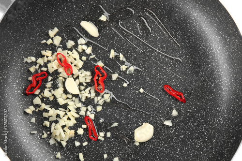 Cooking oil, chopped garlic and chili on frying pan, closeup
