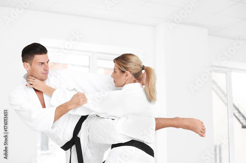 Young man and woman practicing karate in dojo