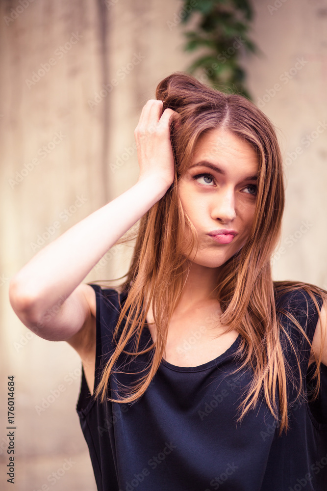 Sensual young woman touching head showing emotion of doubt. Young lady with long hair outdoors. Toned image. Sensual young woman touching head showing emotion of doubt. Young lady with long hair outdoors. Toned image.