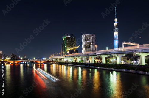 Skyline of Tokyo with skytree and river and lighttrails of boat at night, Tokyo, Japan