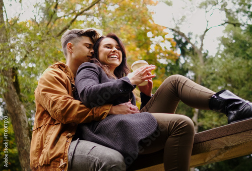 Couple sitting on wooden bridge in autumn park