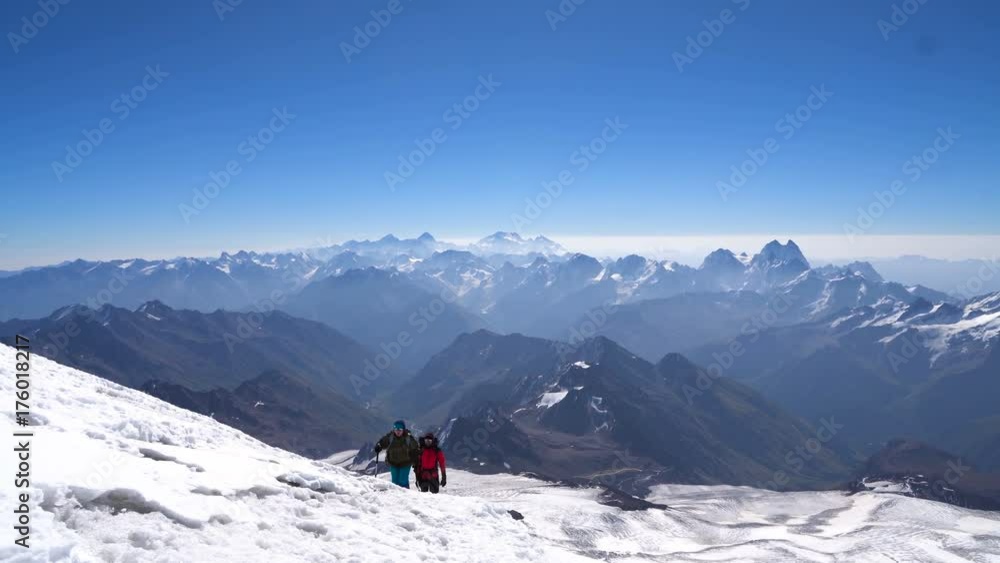Couple of Climbers in crampons coming up to the summit of Elbrus in Caucasus mountains. Snow peak. Couple of Climbers in crampons coming up to the summit of Elbrus in Caucasus mountains. Snow peak.