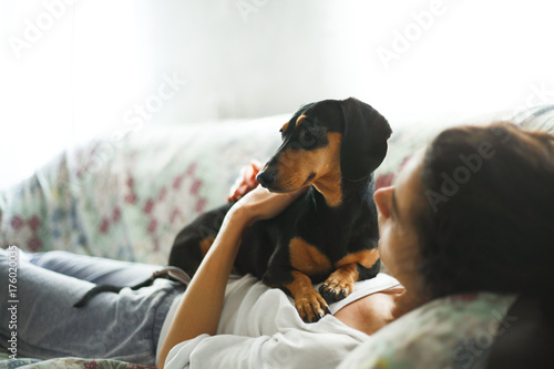 Small black dachshund lying on the couch with a young woman photo