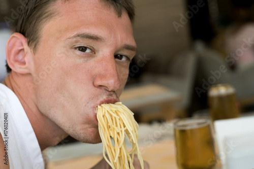 A young guy eating noodles