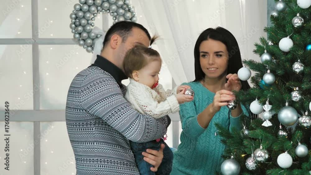 Smiling family decorating a Christmas tree in the living room Smiling family decorating a Christmas tree in the living room