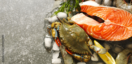 Fresh seafood: salmon steak, shrimps and crabs on stone with copy space