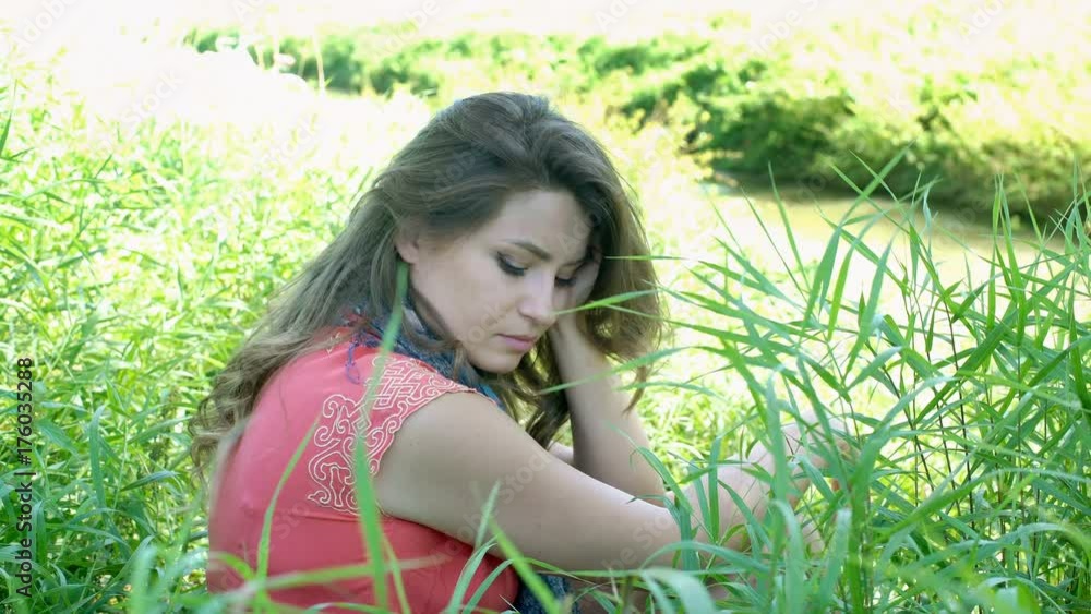 Sad girl sitting in the grass and looking to the camera, steadycam shot
Sad girl sitting in the grass and looking to the camera, steadycam shot