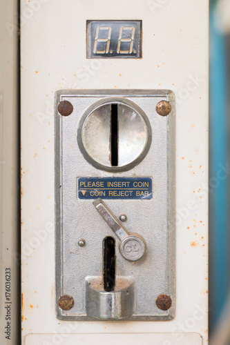 closeup of a metal coin slot coin from a coin operated machine with an entry and exit slots