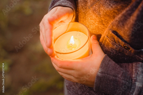 Burning yellow candle in children's hands
