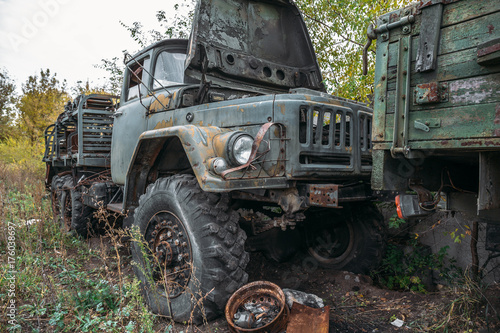 Old rusty abandoned truck, big car among green gras