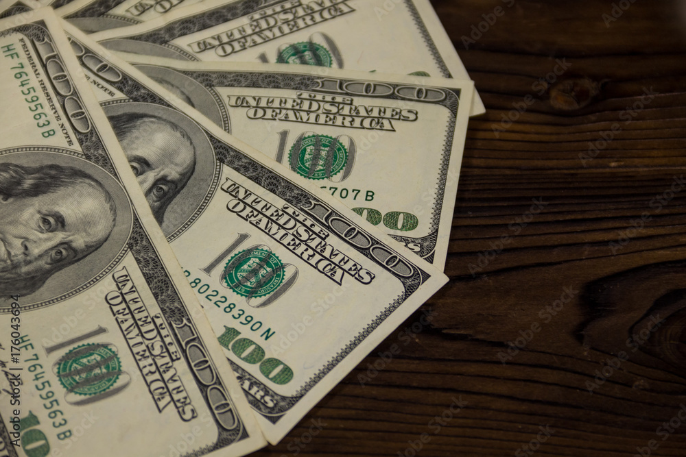 One hundred dollars bills on wooden desk One hundred dollars bills on wooden desk