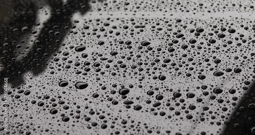 water rain drops on black car with glass coating protection cleaning skin care