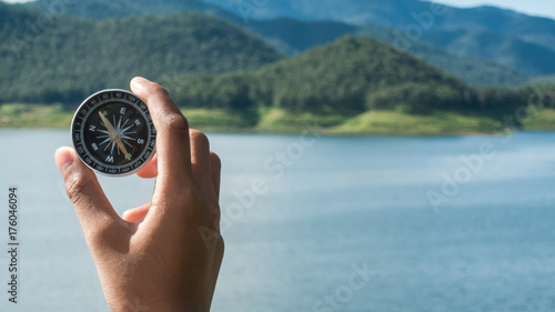 Hand with compass at mountain road at blue sky