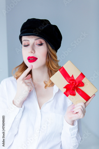 Young redhead woman in hat holding christmas gift box