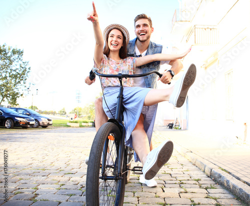 Happy funny young couple riding on bicycle