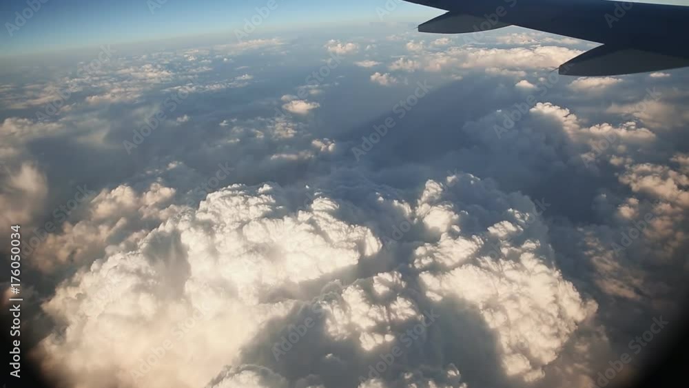 Clouds and sky are visible through the window of a flying airplane. Clouds and sky are visible through the window of a flying airplane.