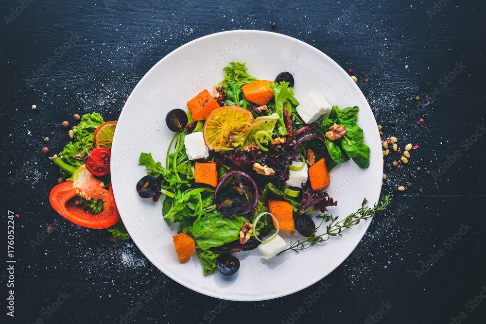 Pumpkin and fresh vegetables salad. Italian cuisine. Top view. Free space for text. On a wooden background. Pumpkin and fresh vegetables salad. Italian cuisine. Top view. Free space for text. On a wooden background.