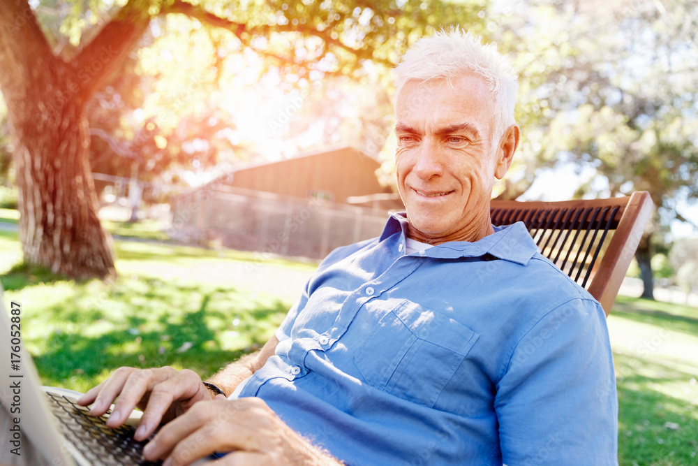 Senior man with notebook sitting in the park Senior man with notebook sitting in the park