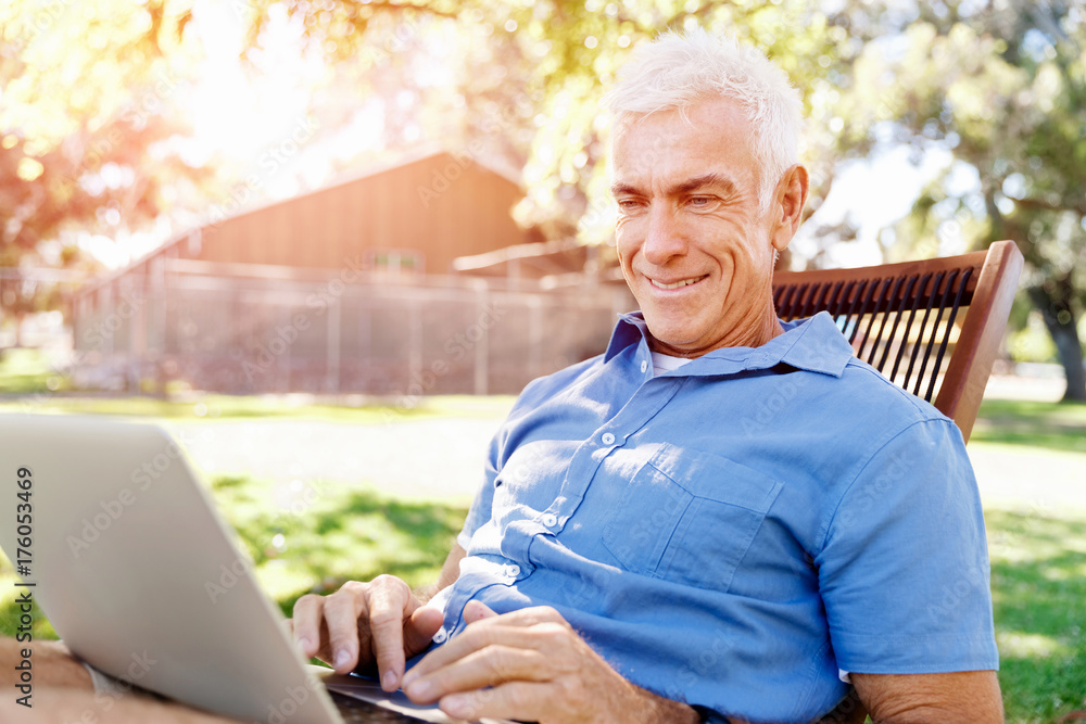 Senior man with notebook sitting in the park Senior man with notebook sitting in the park