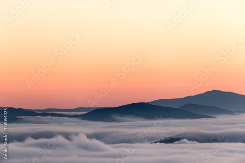 A valley filled by fog at sunset, with mist resembling sea with waves