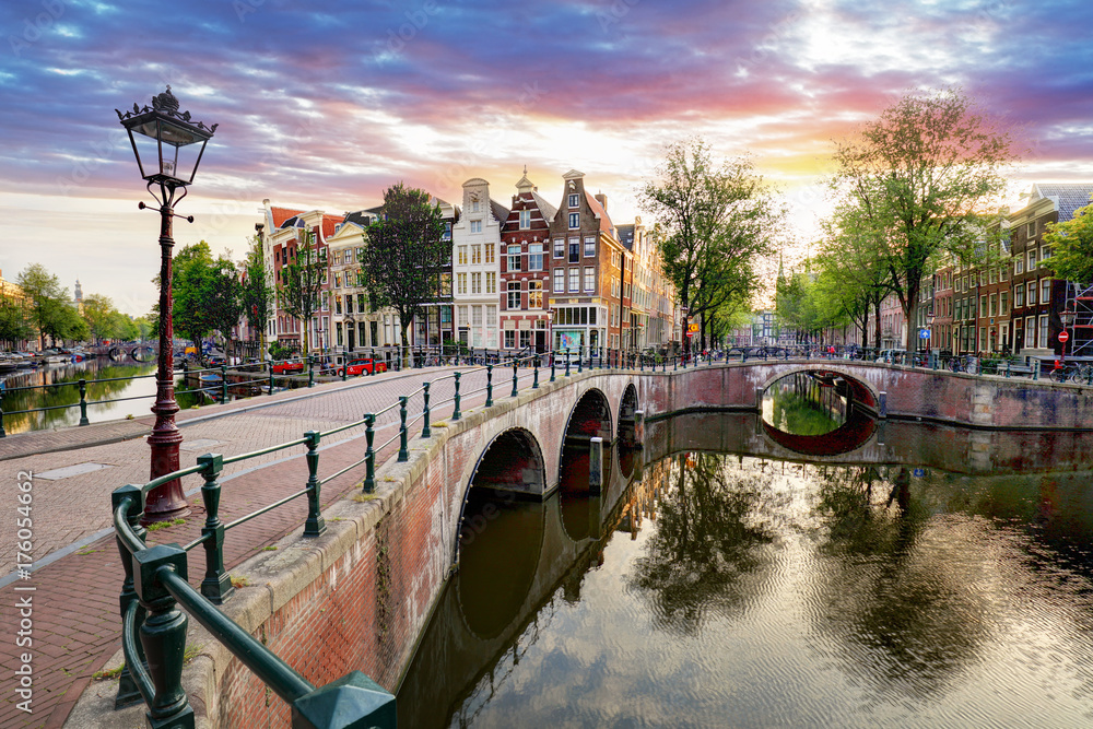 Fototapeta premium Domy nad kanałem amsterdamskim na zachodzie słońca, Holandia