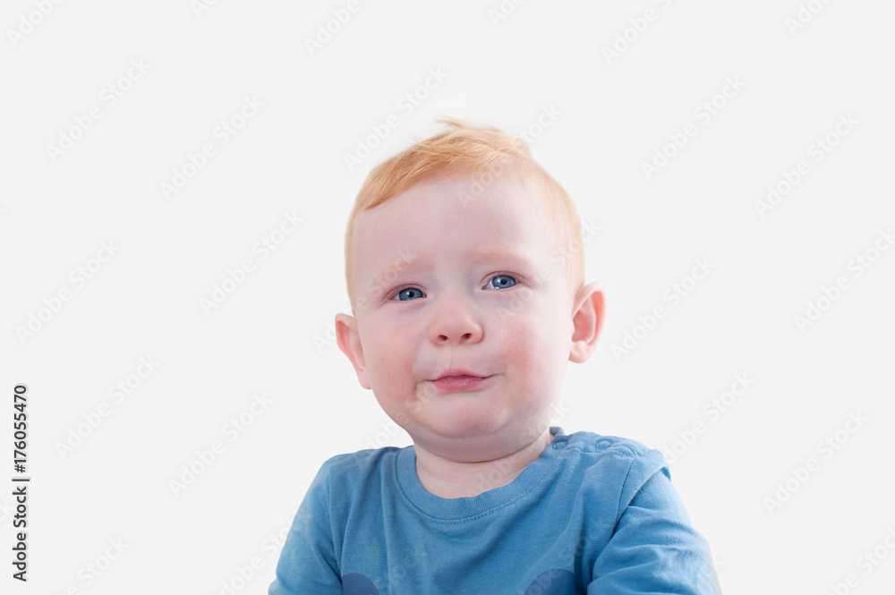 Crying redhead boy in blue tank top on the white background